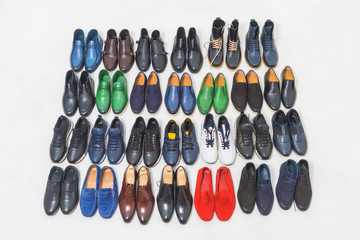 Multicolored men's shoes on a white background. A lot of men's shoes in a row. Types of male shoes. Boots, sneakers and shoes