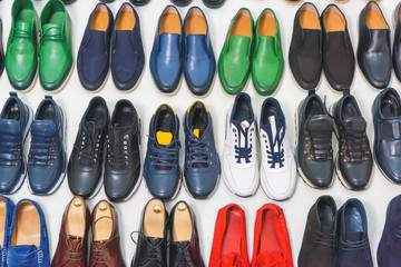 Multicolored men's shoes on a white background. A lot of men's shoes in a row. Types of male shoes. Boots, sneakers and shoes
