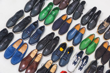 Multicolored men's shoes on a white background. A lot of men's shoes in a row. Types of male shoes. Boots, sneakers and shoes