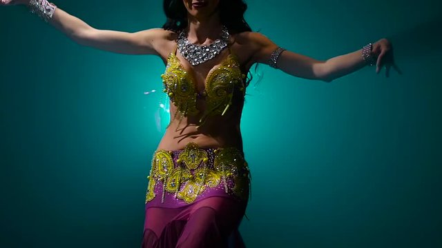 Torso of a exotic female belly dancer . Smoke background. Slow motion. Close up