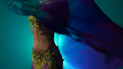 Girl dancing belly dance with a veil in her hands . Smoke background. Slow motion. Close up