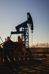 Fototapeta na wymiar Oil pump on the background of blue sky and the morning sun, sun glare on the oil pump