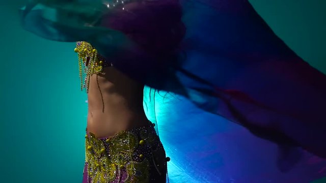 Girl dancing belly dance with a veil in her hands . Smoke background. Slow motion. Close up