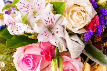 Close up photo from above of romantic bouquet of pink roses, lilies, green leaves.