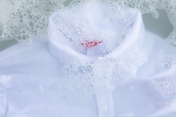 Obraz na płótnie Canvas Soak a cloth before washing, white polo shirt. Top view
