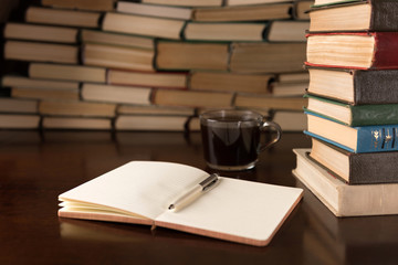 open notebook and cup on the background of books