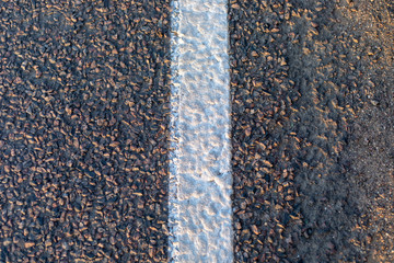 asphalt texture, with a dividing white stripe, bordering a curb