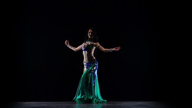 Girl dancing in green dress on black background. Slow motion