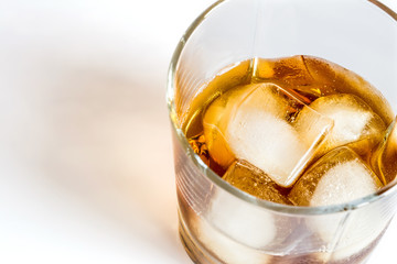 Whiskey with ice close-up in a glass isolated on a white background