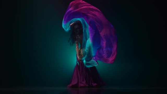 Girl dancing belly dance in dark studio. Smoke background. Slow motion