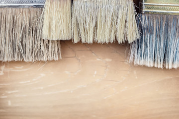 Close-up set of old used pant brushes on rustic wooden background. Vintage dirty paintbrushes