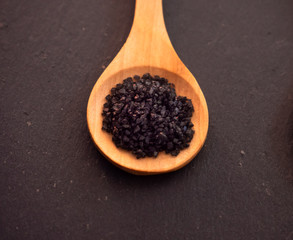 Wooden spoon with hawaii black salt on a slate plate