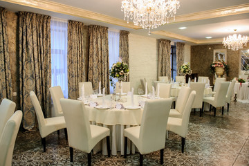 wedding table setting in a banquet hall in white color with curtains
