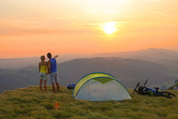 DRONE: Unrecognizable hiker couple observing the picturesque golden sunrise.
