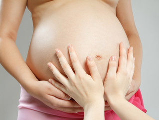 Two hands tender embrace a belly of the pregnant woman