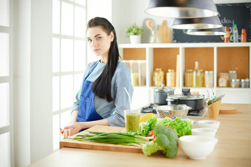 Portrait of young woman standing with arms crossed against kitchen background