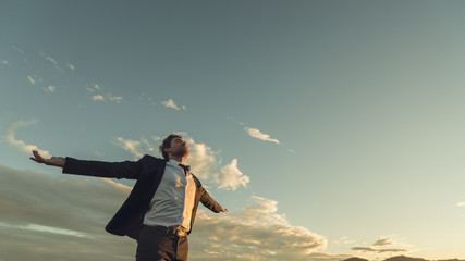 Young businessman relaxing under evening sky