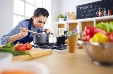 Cooking woman in kitchen with wooden spoon