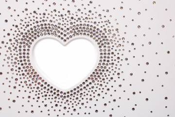 The shape of white heart with crystals around as shiny diamonds