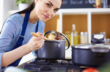 Cooking woman in kitchen with wooden spoon