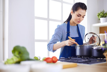 Cooking woman in kitchen with wooden spoon