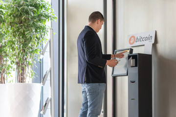 Fototapeta na wymiar Young businessman buying cryptocurrency on ATM machine for buying and selling cryptocurrency.