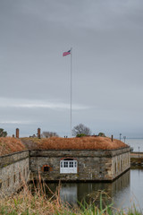 The casemate at Fort Monroe in Virginia with the moat in the foreground, Chesapeake Bay in the background and the American flag flying above.
