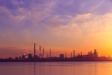 Obraz premium A silhouette of a chemical plant in the setting sun