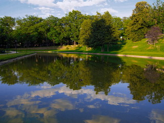 Fototapeta na wymiar Blue and cloudy sky reflection on the park lake