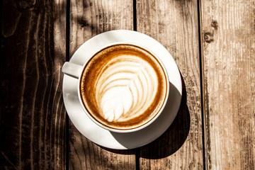 Close up white coffee cup with heart shape latte art foam on black wood table