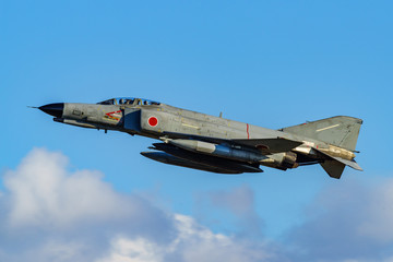 jet fighter F-4 Phantom over white cloud in blue sky