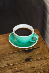 Black coffee in blue cup on wooden background, filter coffee. 