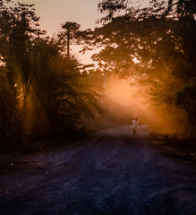 woman walking with child at sunset on dirt road in Guatemalan village