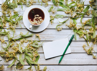 The recipe is written out to the patient, a pen and a notebook. Influenza, acute and respiratory diseases. Tea in a cup of dried flowers of lime on a wooden background. Full recovery, copy space.