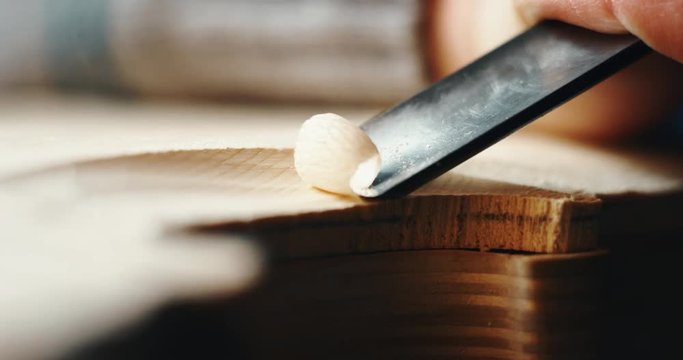 Slow motion macro of master artisan luthier painstaking detailed work on wood violin in a workshop. Shot in 8K. Concept of spiritual instrument, handmade, art, orchestra, artisan, passion for music
