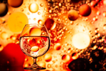 transparent glasses with water with oily drops on colorful background 