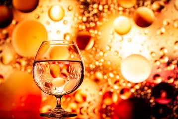 transparent glasses with water with oily drops on colorful background 