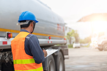 Preforming a pre-trip inspection on a truck,Concept preventive maintenance truck checklist,Truck driver holding clipboard with checking of truck,spot focus.