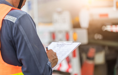 Preforming a pre-trip inspection on a truck,Concept preventive maintenance truck checklist,Truck driver holding clipboard with checking of truck,spot focus.