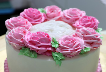 Pink roses and green leaf of butter cream on the white cake.