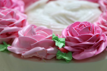 Pink roses and green leaf of butter cream on the white cake.