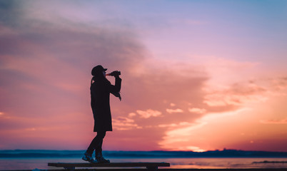A young girl sits on a bench and drinks alcohol alone. Female alcoholism. Depression and loneliness. Get drunk concept. Beautiful picture.