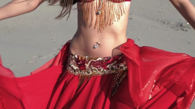 Belly dancing in red dress on the Turkish Patara beach. Filmed in slow motion.