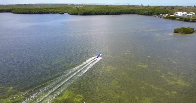 AERIAL: tracking a boat speeding through the waters off the shoreline of Key Largo, Florida.