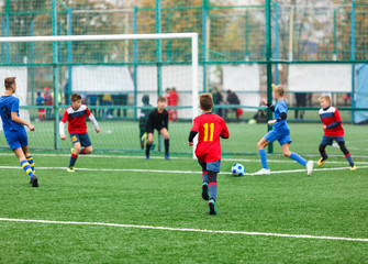 Football training for kids. Boys in blue red sportswear on soccer field. Young footballers dribble and kick ball in game. Training, active lifestyle, sport, children activity concept 