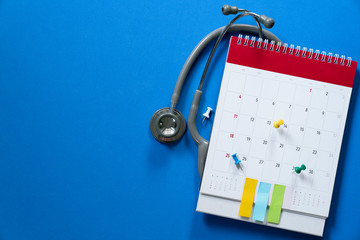 Top view of stethoscope and calendar on the blue background, schedule to check up healthy concept
