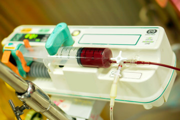 Blood in syringe pump machine transferring blood to a sick newborn baby in a hospital.