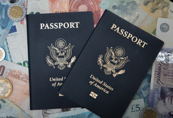 Two USA Passports with a backdrop of foreign currency meant to illustrate international, exotic, or romantic travel around the world