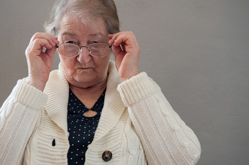 Elderly woman with beautiful wrinkled face is holding pills in her hands to choose medicines. Selective focus depth of field