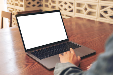 Mockup image of a woman using and touching on laptop touchpad with blank white desktop screen on wooden table